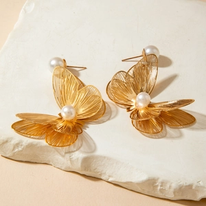 Detailed view of golden butterfly earrings with hollow wings and central white pearl