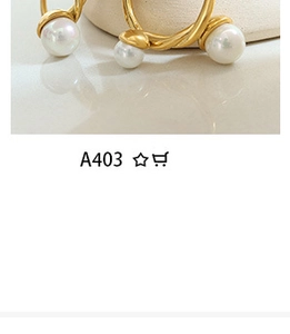 Detail shot of golden twisted round earrings with large white pearl on reflective surface