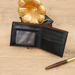 Detail of bifold wallet showing black litchi leather and brown interior with card slots