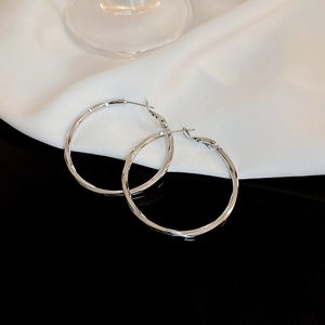 Detailed view of silver hoop earrings with twisted geometric facets on reflective surface