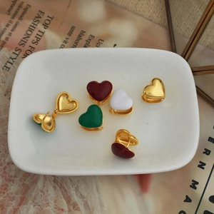 Detail of gold-plated heart hoop earrings with colorful enamel on a decorative tray