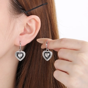 Detail view of heart earring featuring black enamel border and sparkling heart-shaped zircon
