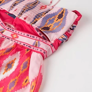 Detail of bohemian halter dress featuring pink ethnic print and elastic waist cut-outs
