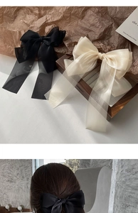 Detail of elegant black and beige sheer tulle bow hair clips shown on a wooden tray