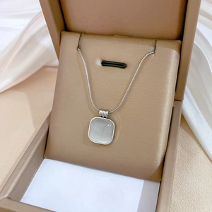Close-up of square opal pendant on a silver snake chain inside a brown jewelry box