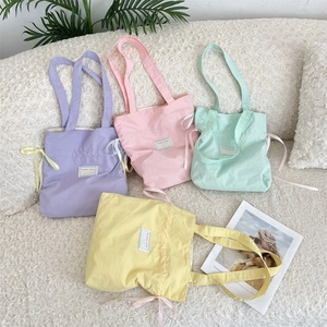 Macro shot of candy-colored canvas tote bags with drawstring ribbons on a plush surface
