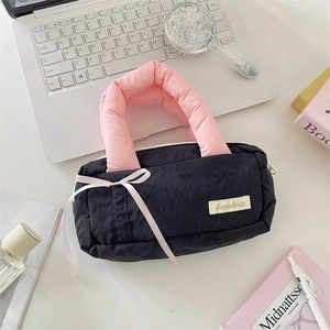 Detail of black nylon storage bag with pink puffy handle and decorative bow accents