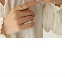 Close-up of gold-tone cutout interlocking link ring worn on index finger with a chic shirt