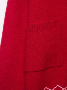 Detail of red knit cardigan showing the ribbed pocket and white geometric pattern