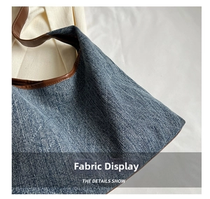 Macro detail of blue quilted denim fabric and brown leather trim on the tote bag