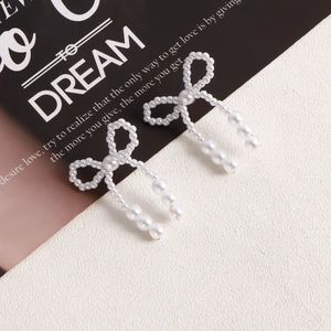 Detailed macro view of handmade pearl bow earrings with elegant dangling tassels