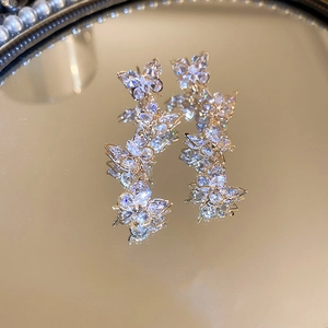 Macro shot of silver butterfly tassel earrings with sparkling cubic zirconia on mirror