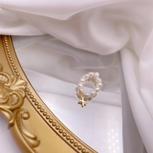 Detailed macro view of baroque pearl ring featuring a dangling gold cross charm