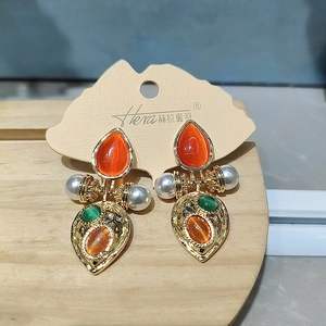 Detail showing vintage gold earrings with orange pear-shaped stones and faux pearls