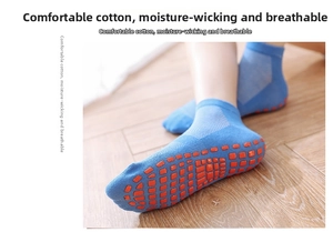 Detailed close-up of blue non-slip yoga socks with orange silicone grips on wooden floor