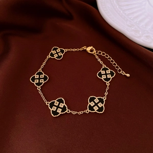 Detailed close-up of gold plated four-leaf clover bracelet with black stones and zircon