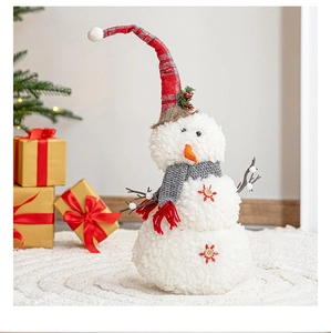 Detail of plush Christmas snowman with red plaid hat and twig arms in festive setting