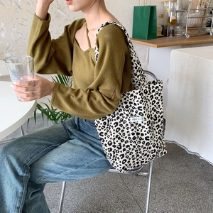 Black and white leopard print canvas tote bag carried by a model in a cozy cafe