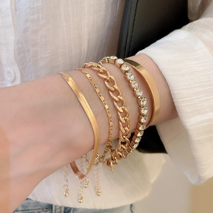 Détail d'un ensemble de 5 bracelets dorés avec chaîne serpent, maillons et strass brillants