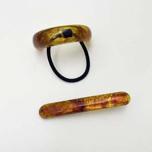 Detail view of resin hair set with marble amber pattern U-shaped pin and elastic hair tie