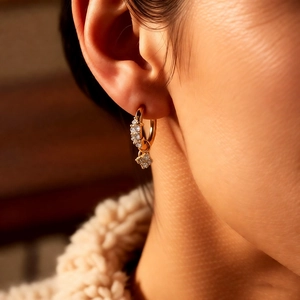 Vue détaillée des boucles d'oreilles fleur dorées avec zircons sur une oreille