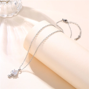 Close-up of a silver key pendant with a large clear zircon on a beige display stand