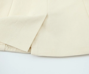 Gros plan sur la texture du sergé beige et les doubles coutures de précision du bas