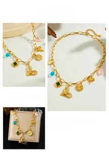 Detail of gold layered chain necklace featuring colorful gemstones and heart pendants