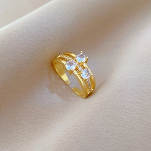Three-layer gold-plated open ring with sparkling pavé zircons on a beige silk background