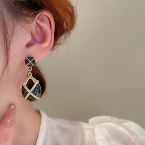 Gros plan de boucles d'oreilles goutte vintage noir et or avec cadre géométrique sur mannequin
