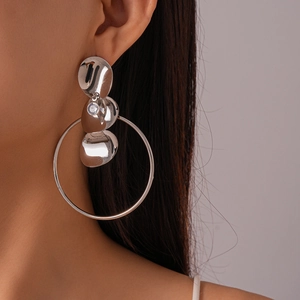 Primo piano di orecchini geometrici in argento con dischi metallici e zirconi