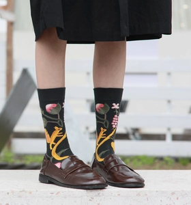 Close-up of black cotton socks featuring floral and squirrel patterns on a model