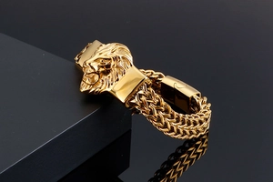 Detail shot of golden lion head buckle on a thick double-row braided metal men's bracelet