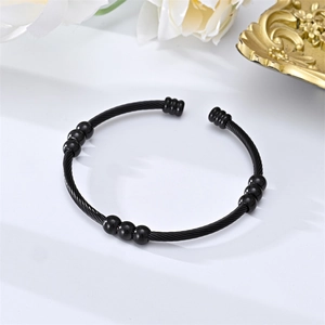 Macro detail of black twisted cable cuff bracelet featuring elegant round steel beads