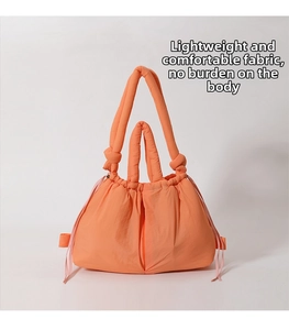 Detail of orange puffer tote bag showing soft drawstring closure and padded texture