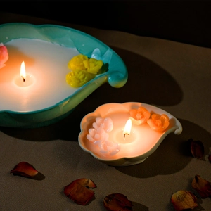 Nahaufnahme von Muschel-Duftkerzen mit bunten Blumen-Wachsstücken in warmem Licht