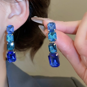 Close-up of elegant gradient blue square gem earrings showing four stones on a model