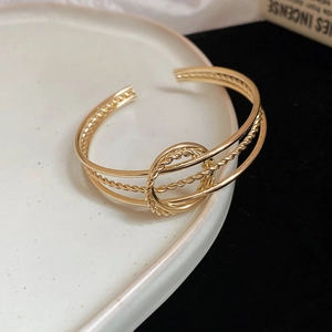 Macro shot of gold twisted metal bangle with triple-layer structure and ring detail