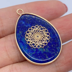 Close-up of lapis lazuli water drop pendant with golden mandala overlay and metal frame