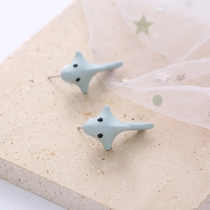 Detailed view of light blue shark stud earrings on a decorative marble surface