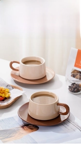 Details von nordischen Keramik-Kaffeetassen mit cremefarbenem Korpus und braunem Griff und Untertasse