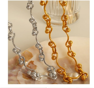 Detailed close-up of wavy gold and silver steel chain links with polished bead accents