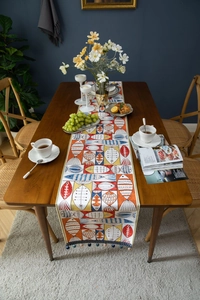Detail of chenille table runner with geometric fish patterns and decorative tassels