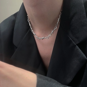 Gothic silver heart necklace with thorn-like wire design worn by a model