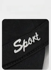 Close-up of a silver 3D metal Sport logo on black twill fabric of an adjustable tactical cap