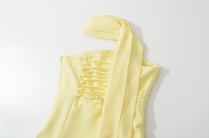 Dettaglio dell'abito giallo pallido con lacci incrociati sulla schiena e foulard