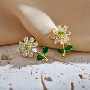 Elegant gold-plated daisy stud earrings with green and white zircon on stone background