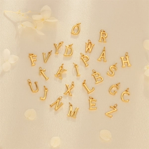 Elegant gold alphabet charms set A-Z for DIY necklaces on a minimalist textured background