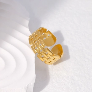 Detailed view of the gold hollow-out woven texture and geometric design on the wide band ring