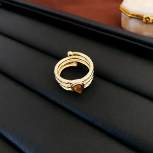 Detail of a triple-layer gold ring with teardrop brown stone on a black display stand